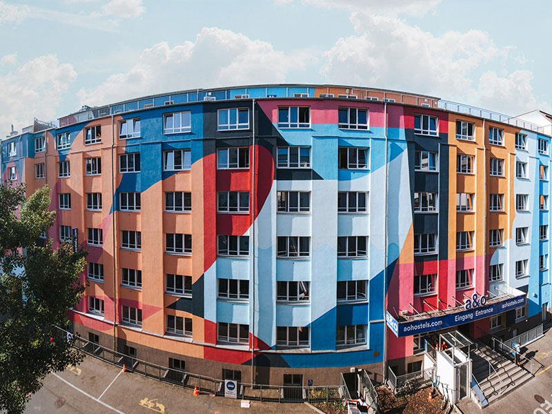 The exterior facade of a&o Vienna Hauptbahnhof features a mural.